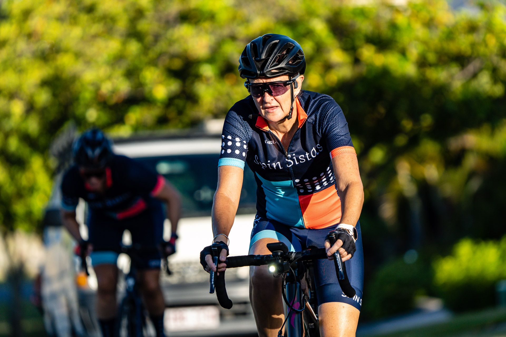 A smiling Spin Sistas cyclist riding in morning light
